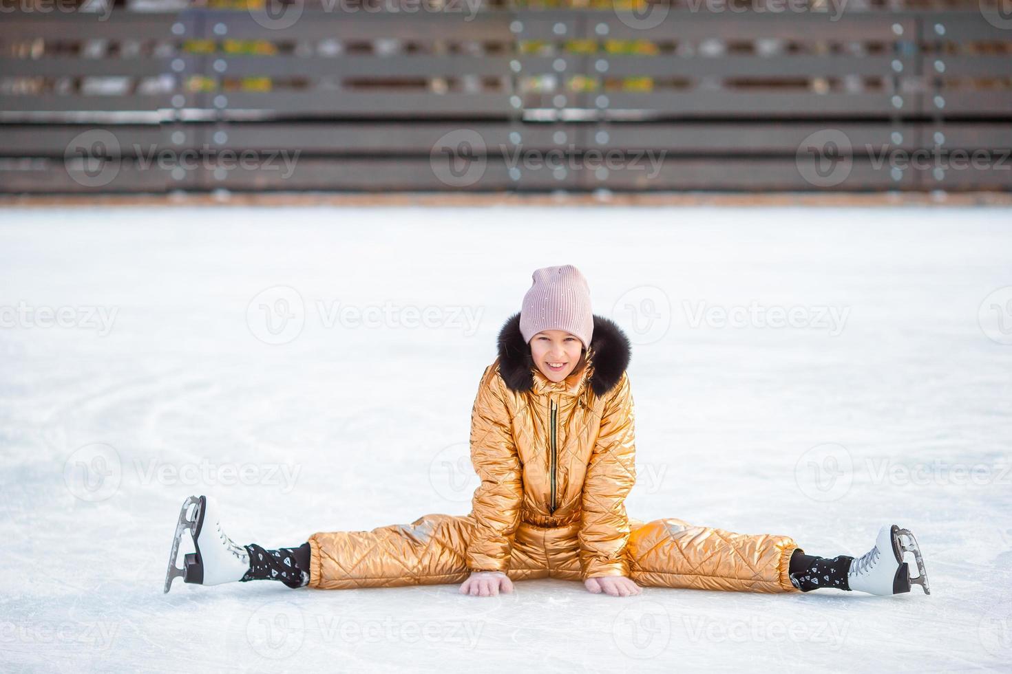 Little adorable girl sitting on ice with skates after fall photo