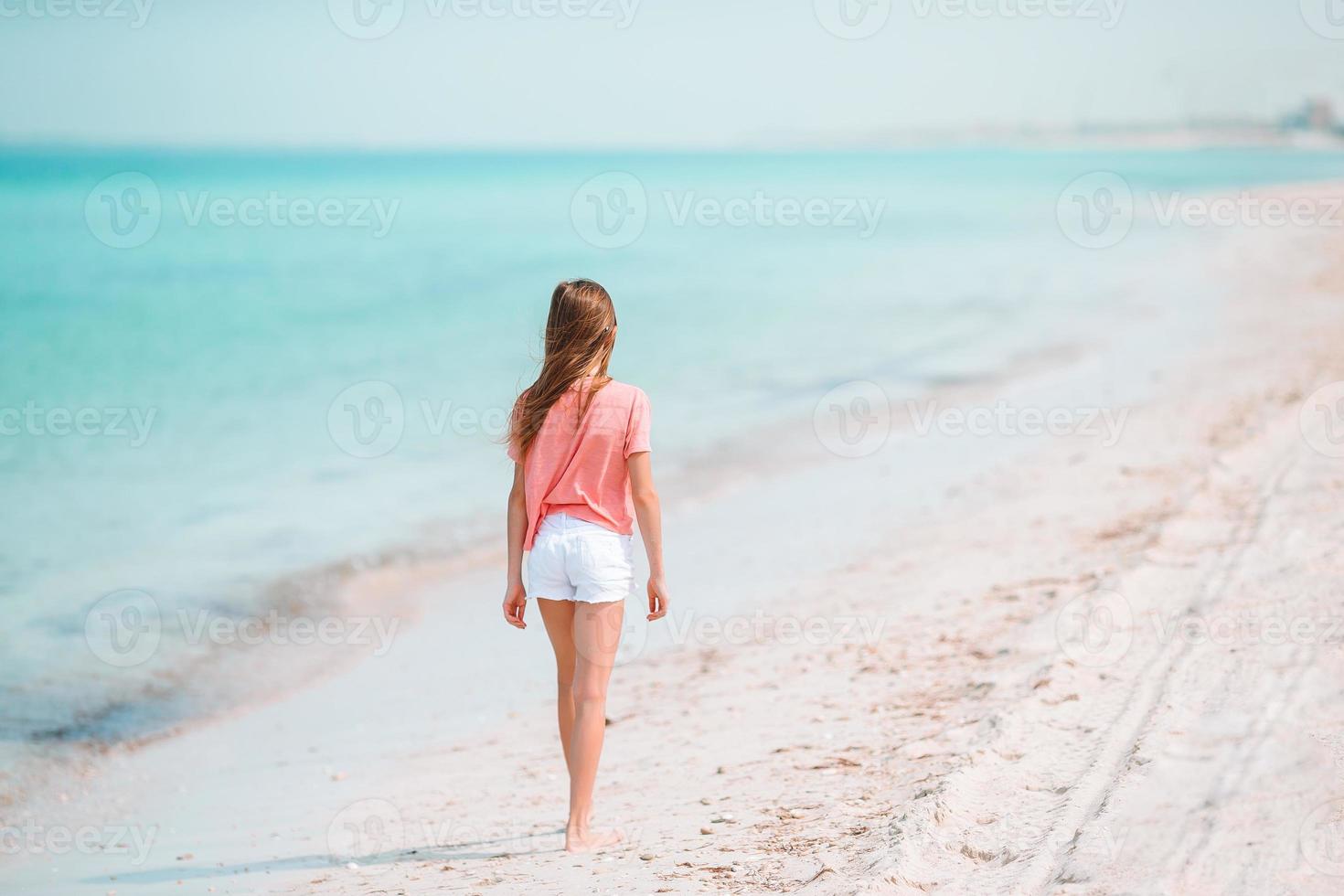 Adorable active little girl at beach during summer vacation photo