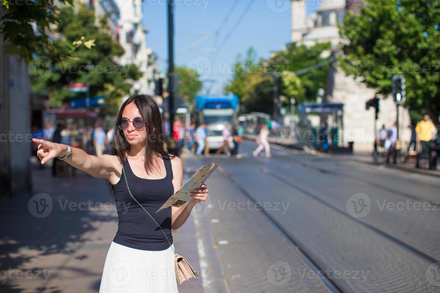 Young beautiful traveling woman with map in the city photo
