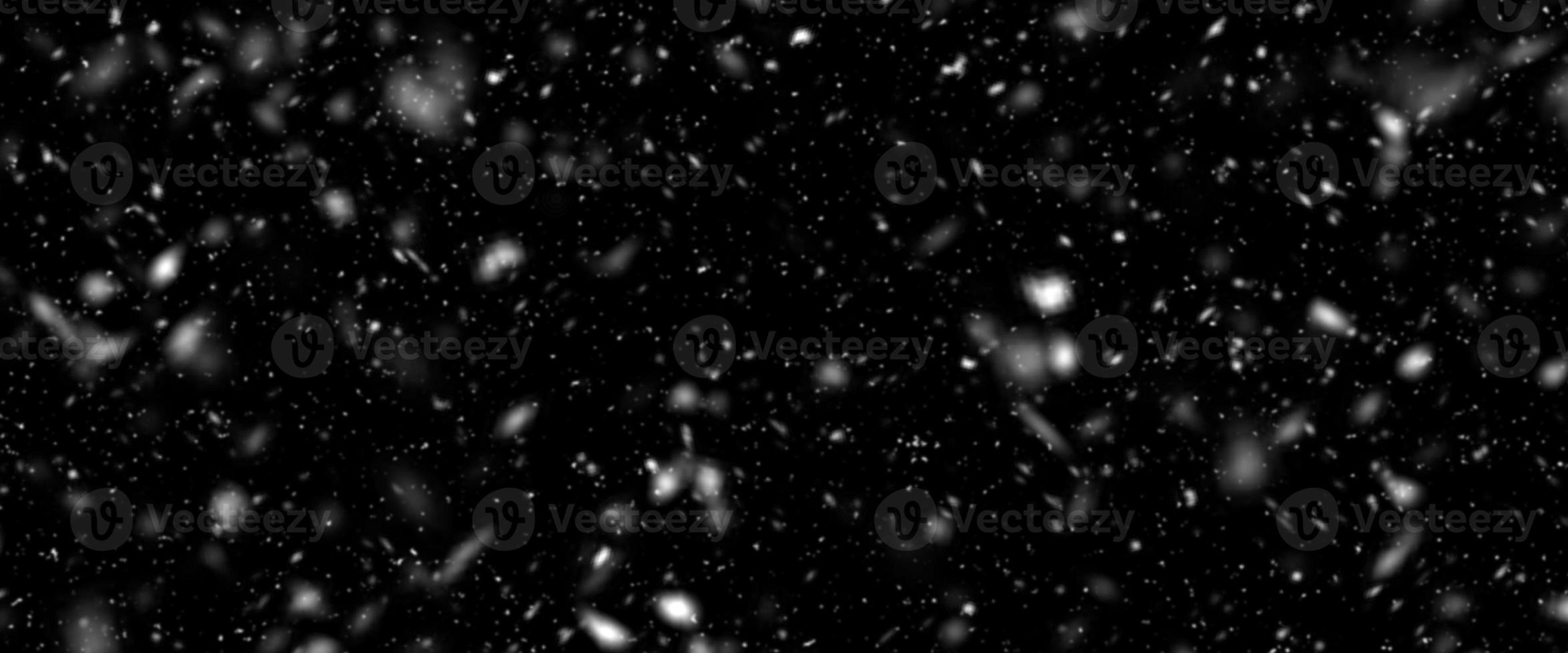 Snowfall bokeh on black background. Many snowflakes in flying in the air. Winte night snowfall and blizzard of snow at. Blur bokeh light effect creative background. photo