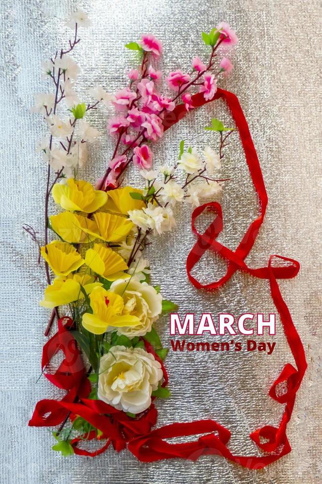 Figure 8 made of ribbon and artificial flowers for International Women's Day celebration on silver background with space for text photo