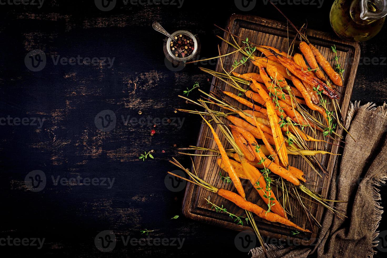 Baked organic carrots with thyme, honey and lemon. Organic vegan food. Top view photo