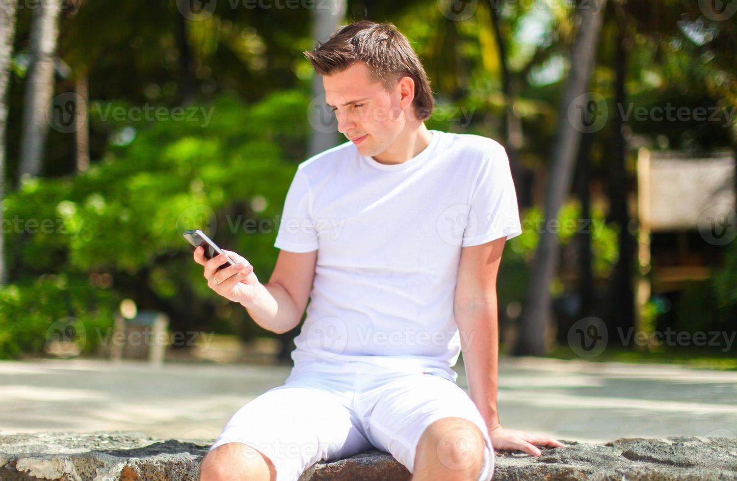 Young man talking on phone during tropical beach vacation photo