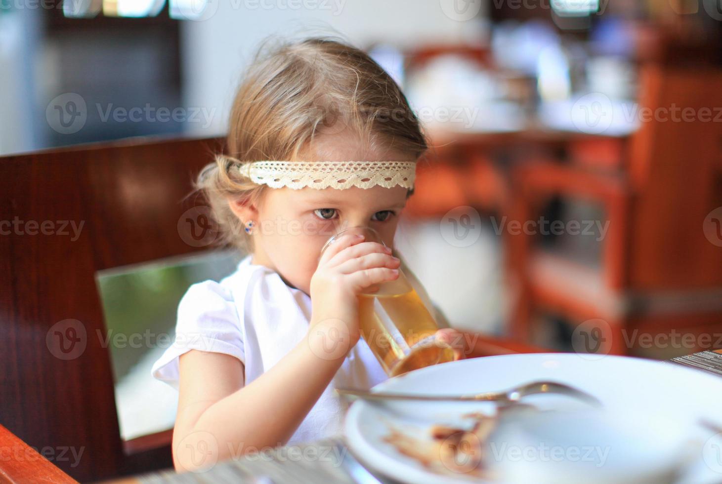 Adorable little girl having breakfast at restaurant photo