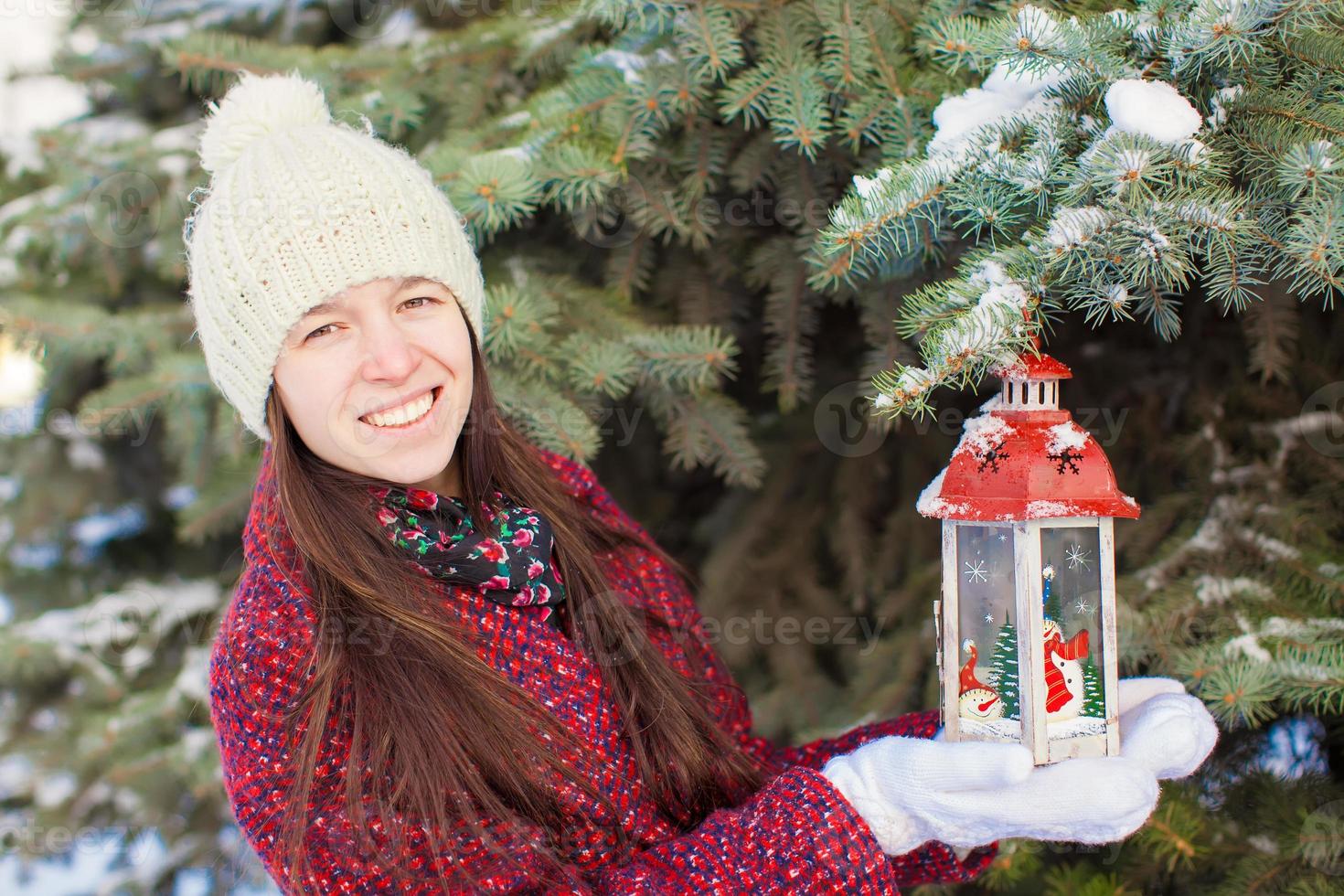 Young beautiful happy woman with red Christmas lantern in the snow photo