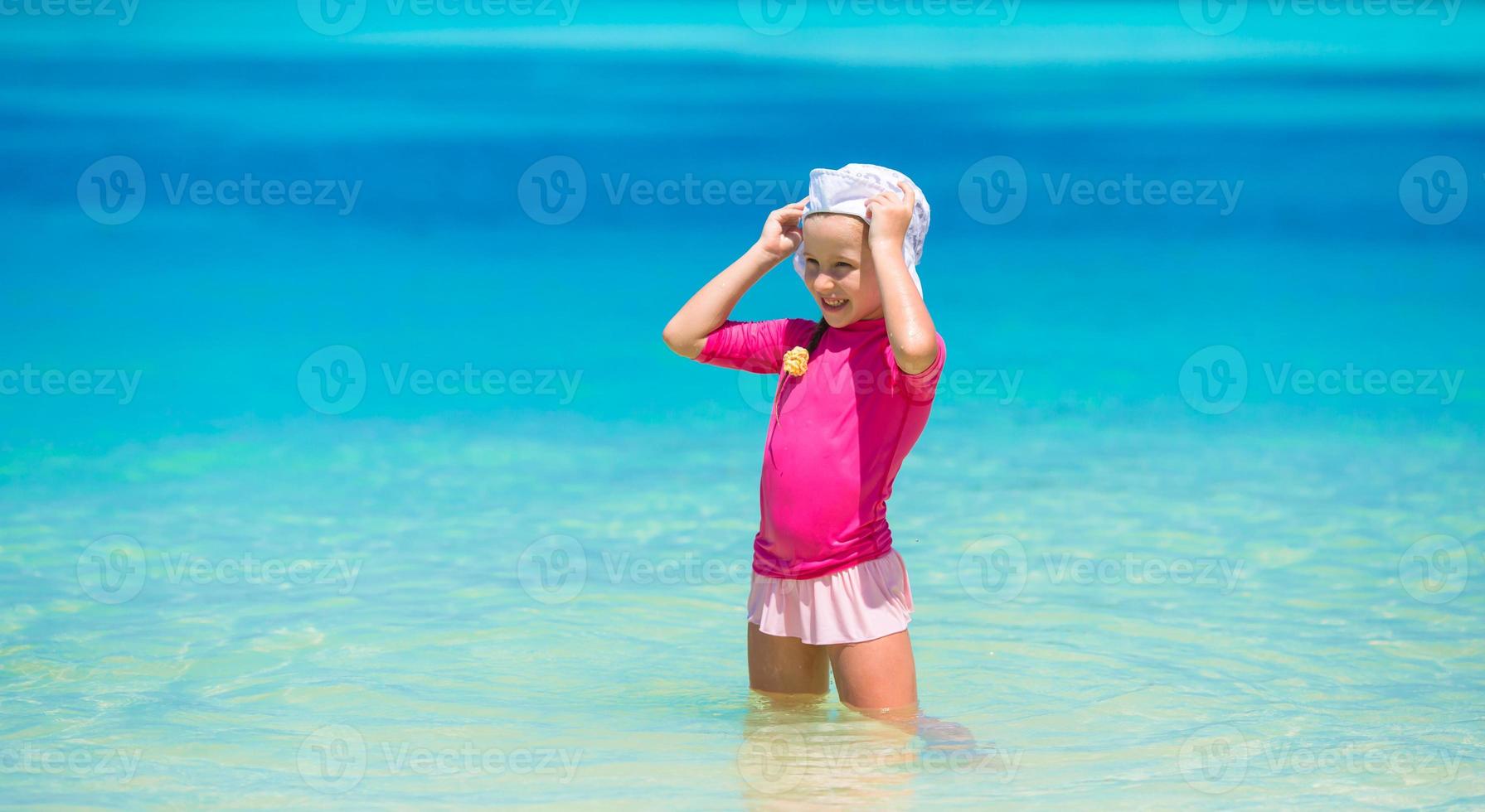 Adorable happy little girl have fun at shallow water on beach vacation photo