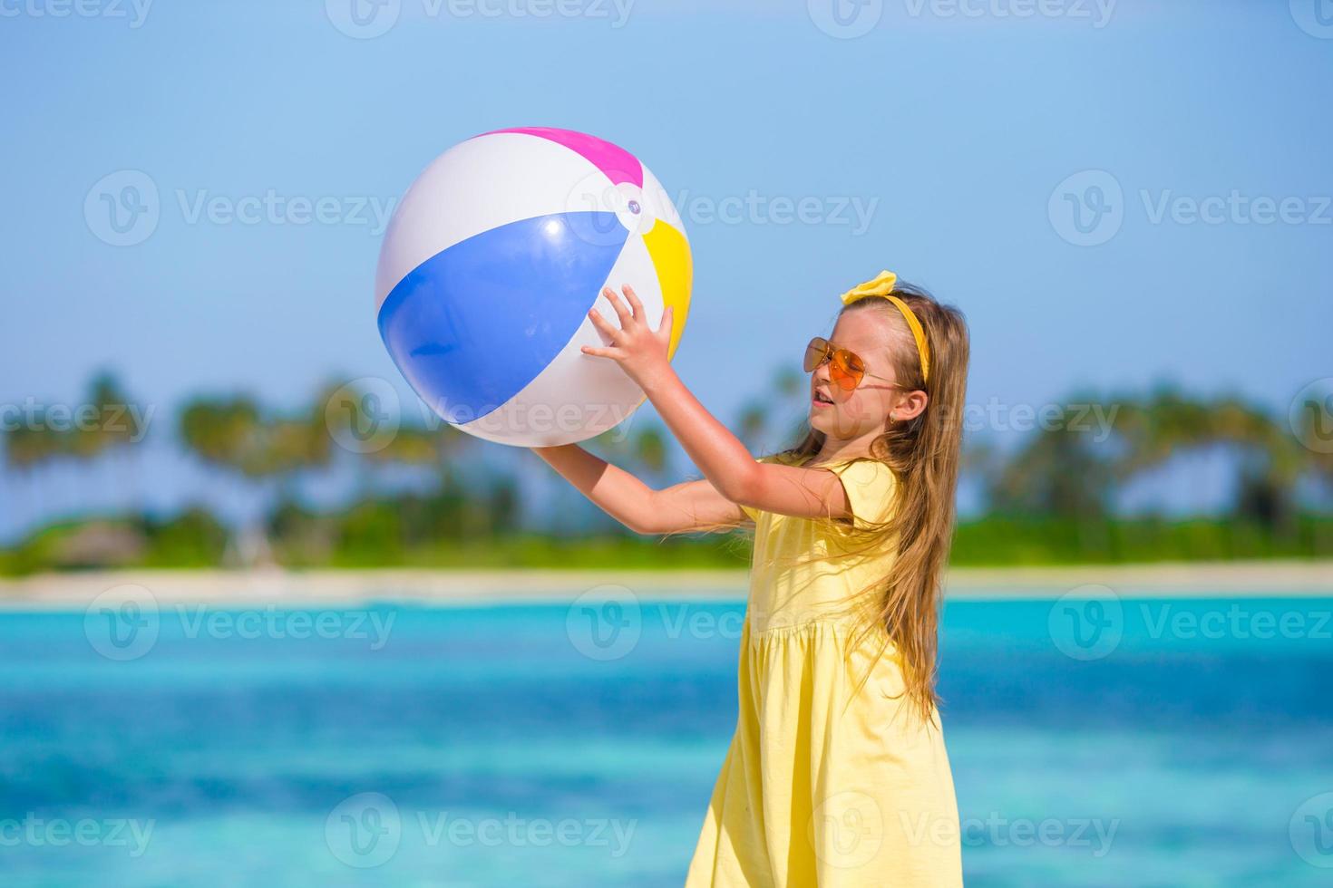 Little adorable girl playing on beach with ball outdoor photo