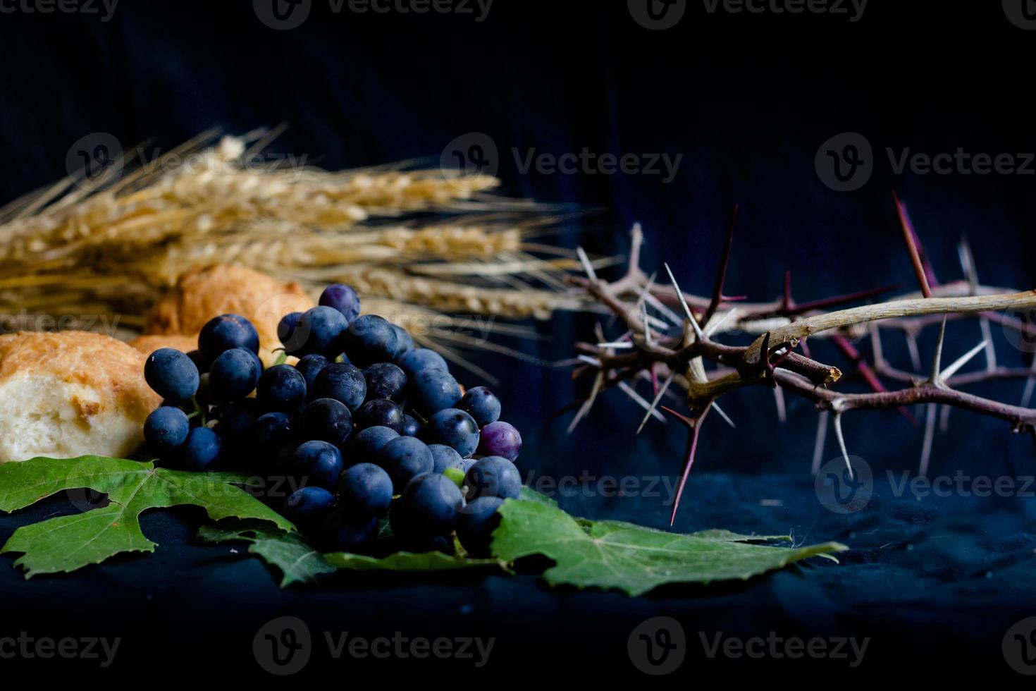 wheat grapes bread and crown of thorns on black background as a symbol of Christianity photo