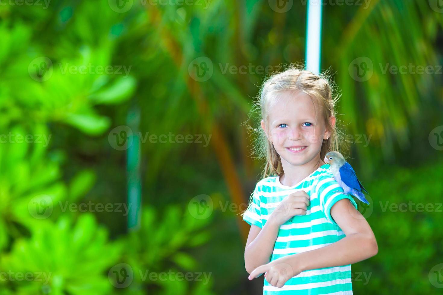 Adorable happy girl at beach with colorful little bird photo