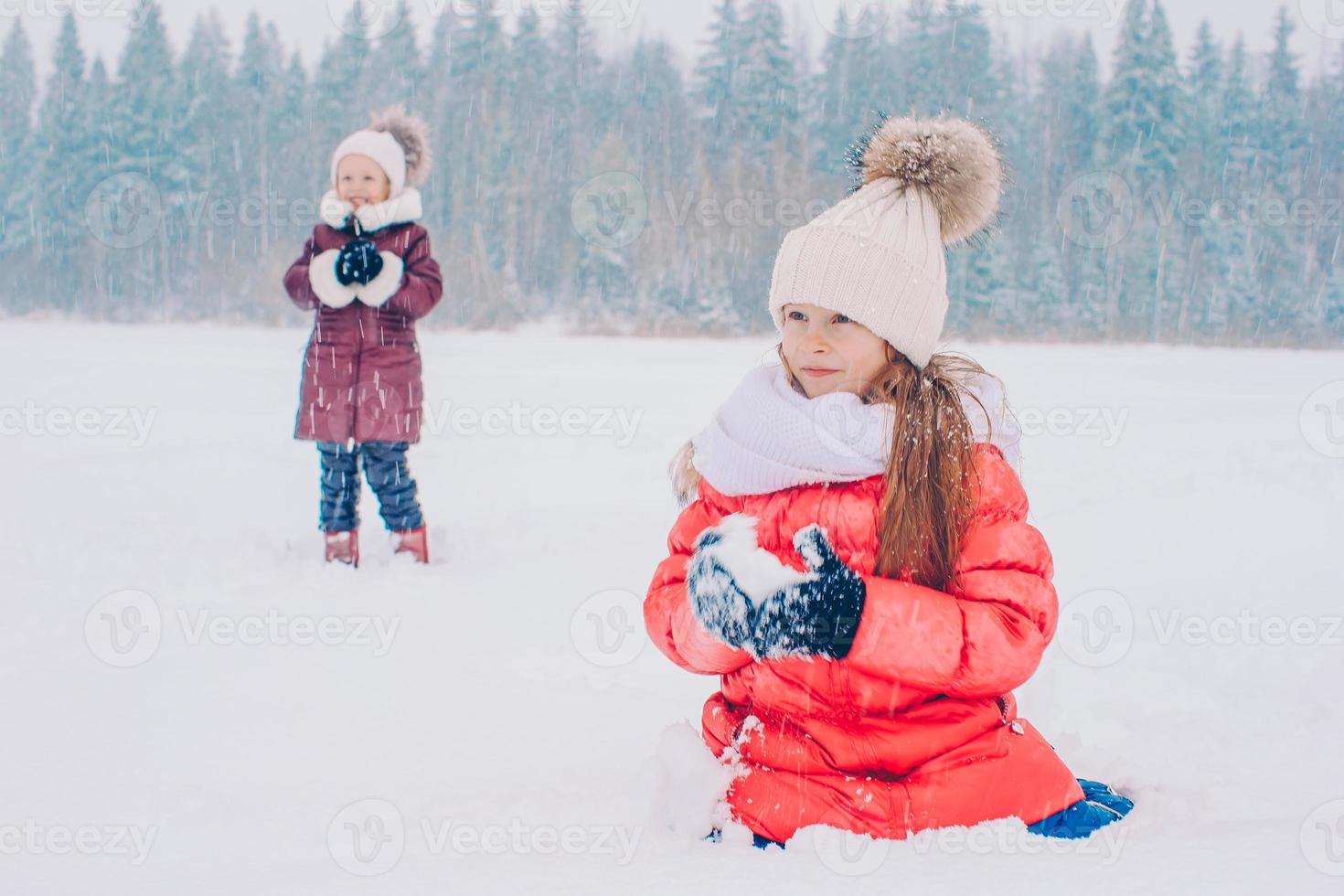 Adorable little happy girls sledding in winter snowy day. photo