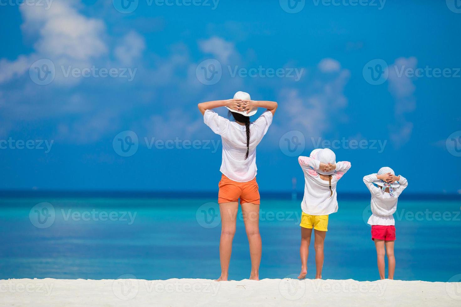 adorables niñas y madre joven en la playa blanca tropical foto