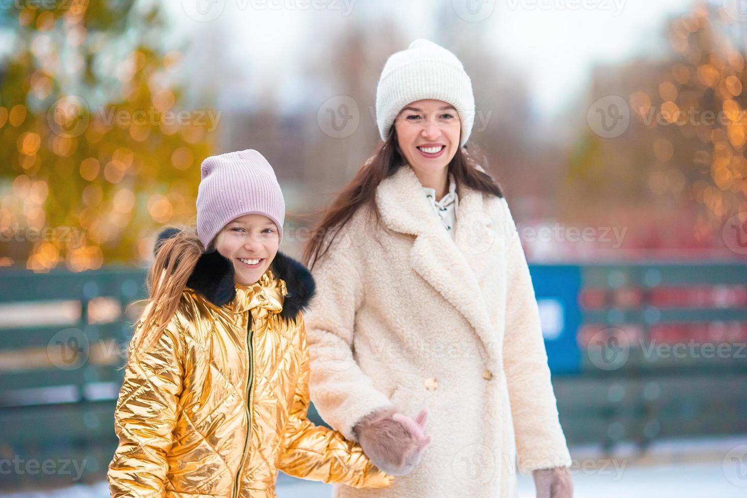 niña adorable con su madre patinando en la pista de hielo foto