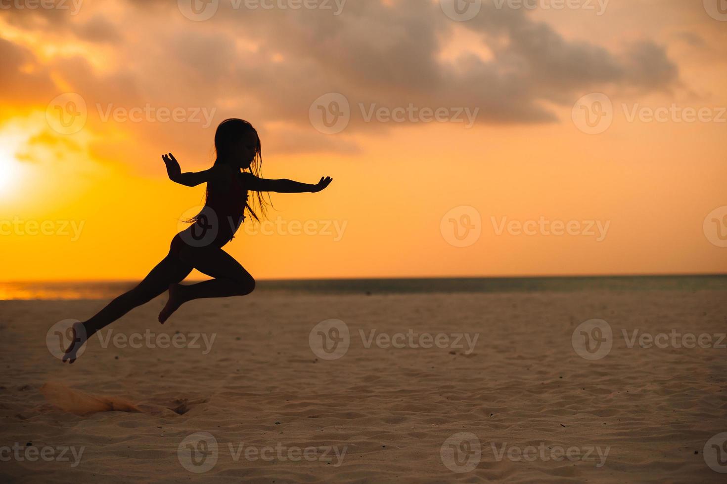 Adorable happy little girl on white beach at sunset. photo