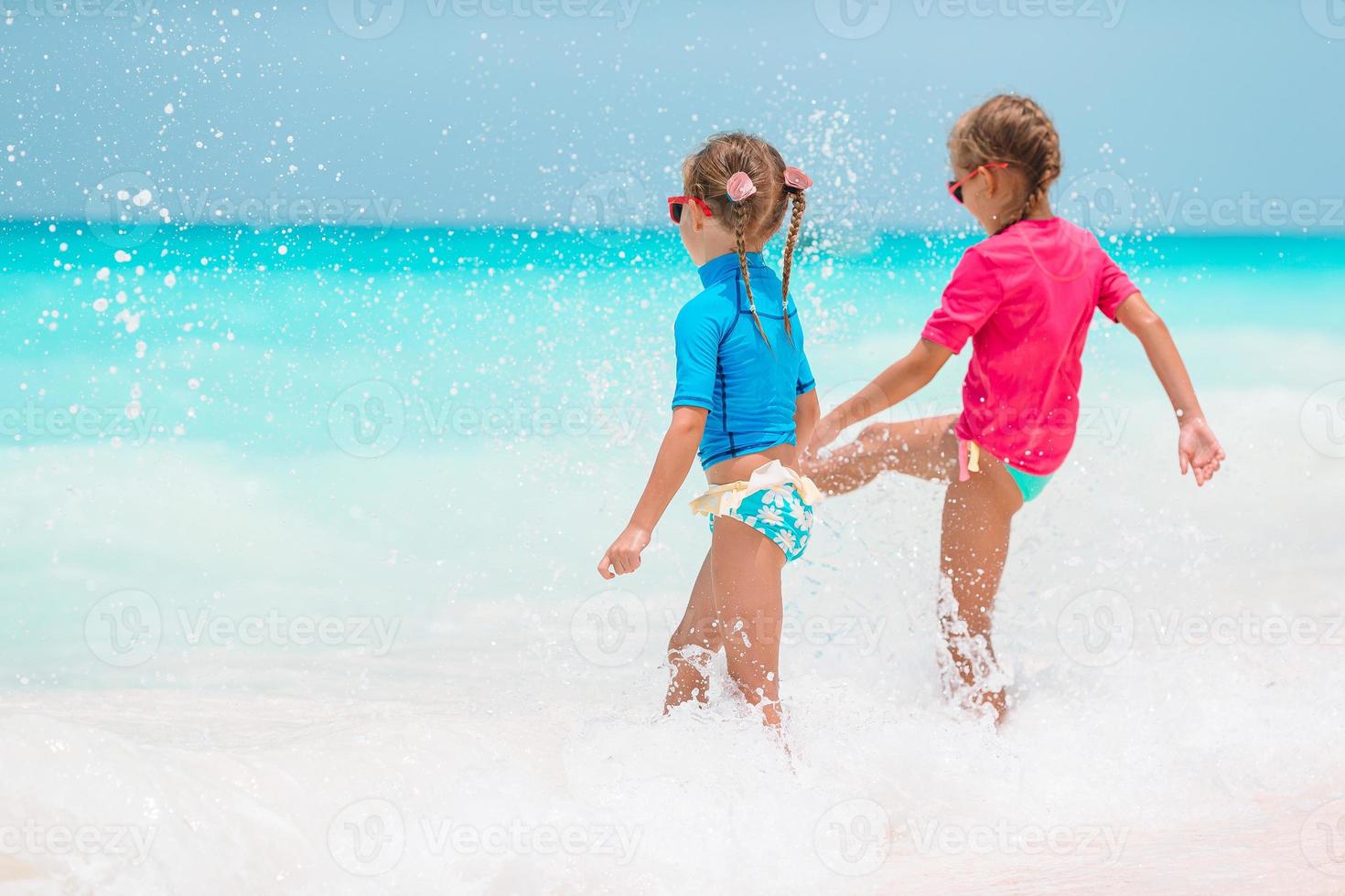 Adorable little girls have fun on white beach during vacation photo
