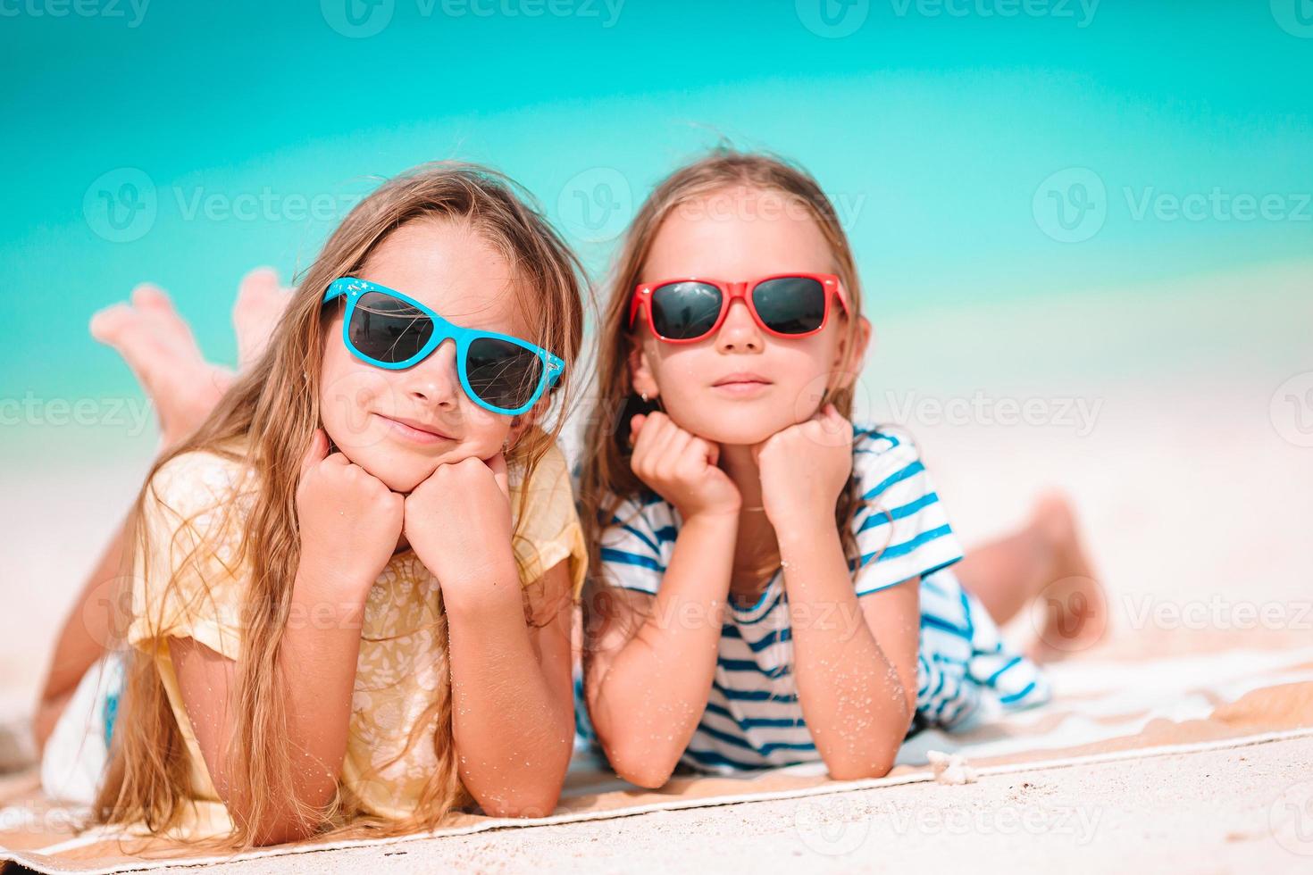 Cute little girls at tropical beach together. Adorable little sisters on the seashore during summer vacation photo