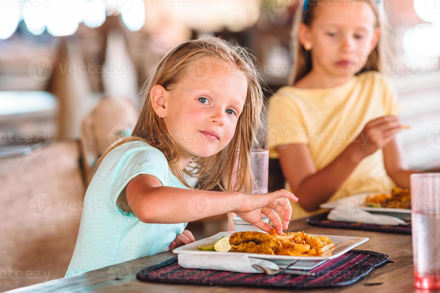 Adorable little girl having breakfast at outdoor cafe photo