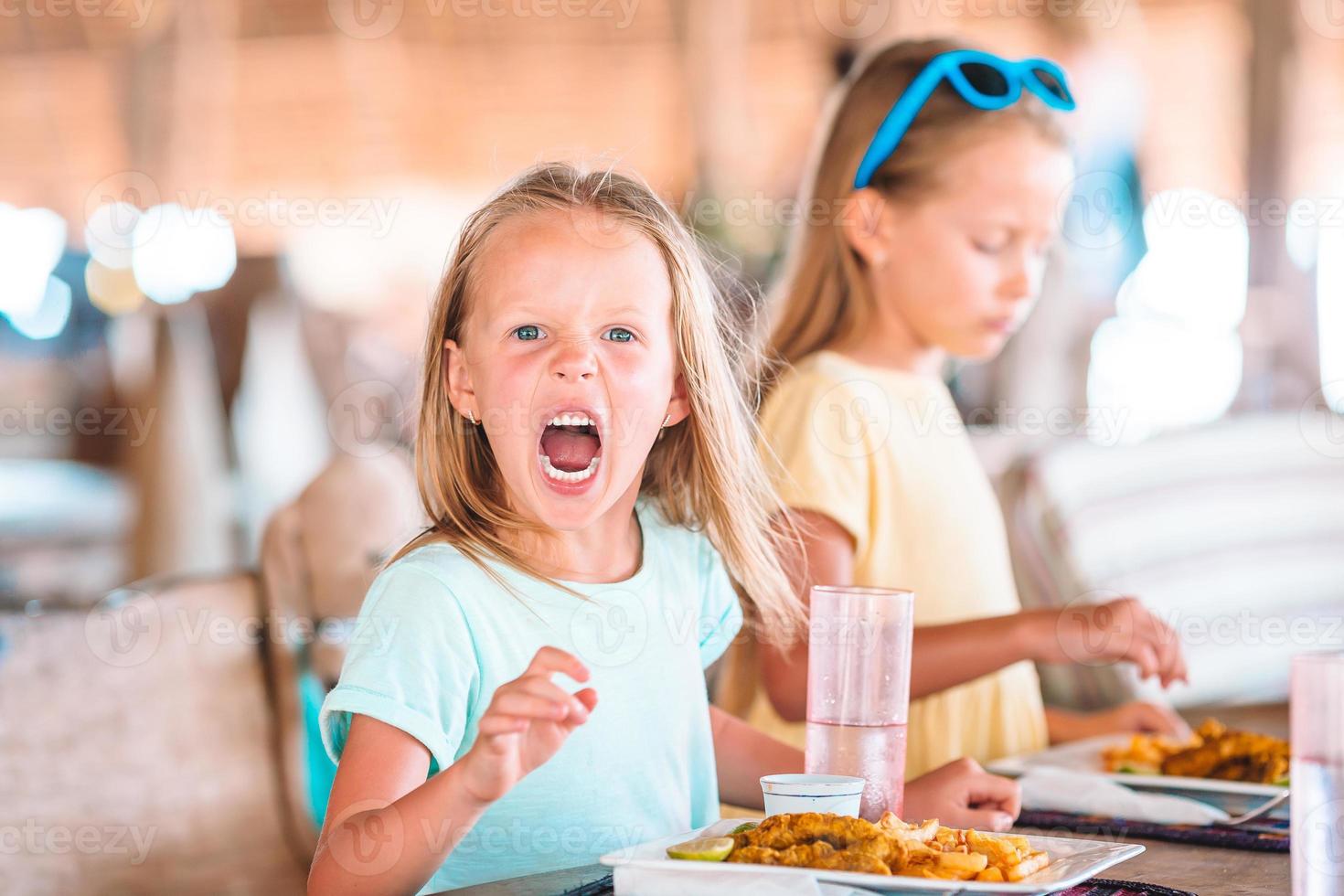 Adorable little girl having breakfast at outdoor cafe photo