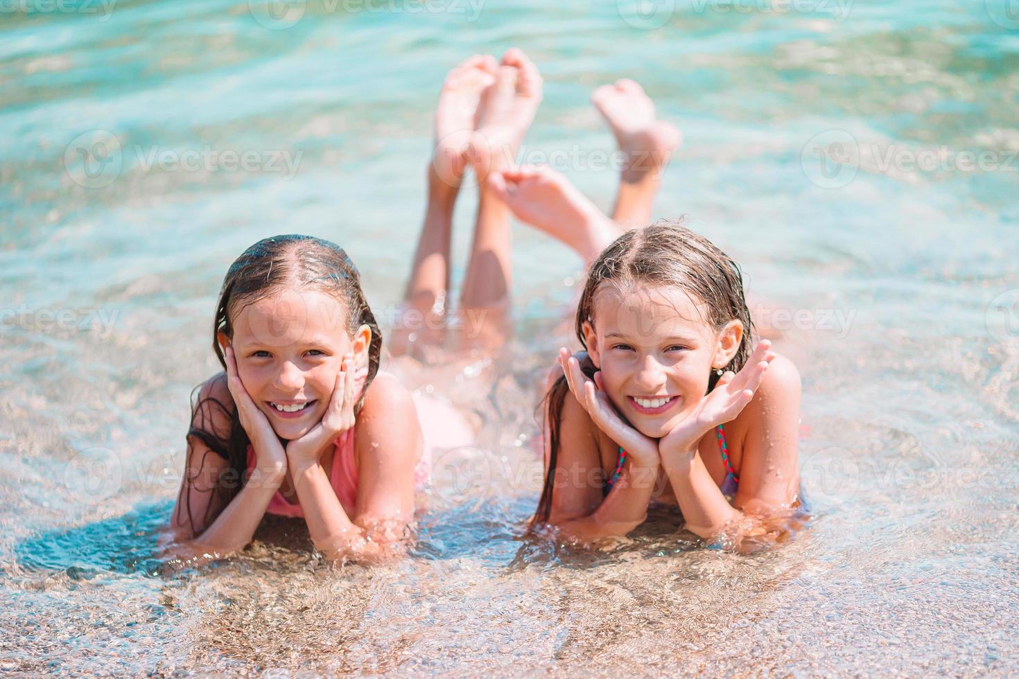 Adorable little girls having fun on the beach photo