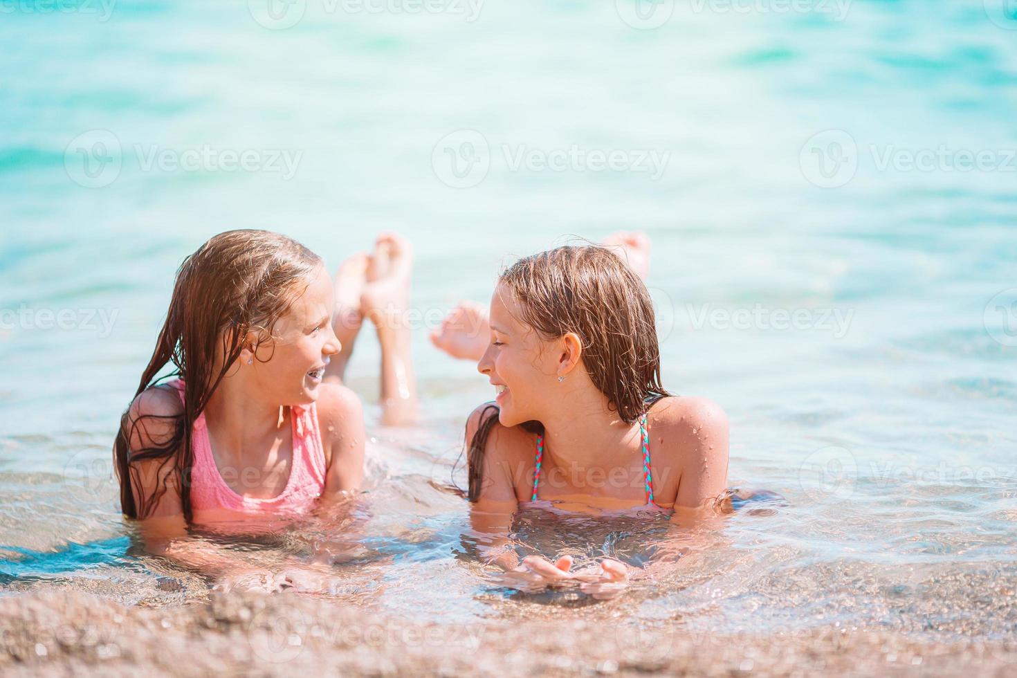 Adorable little girls having fun on the beach photo