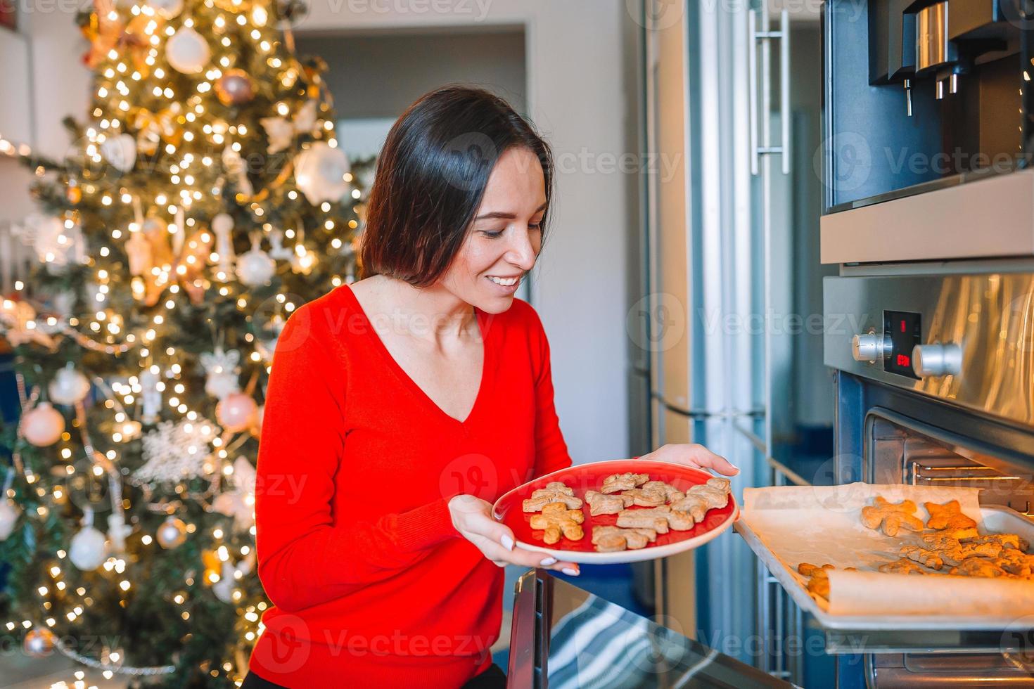 Young woman in Christmas hat baking gingerbread at home. photo