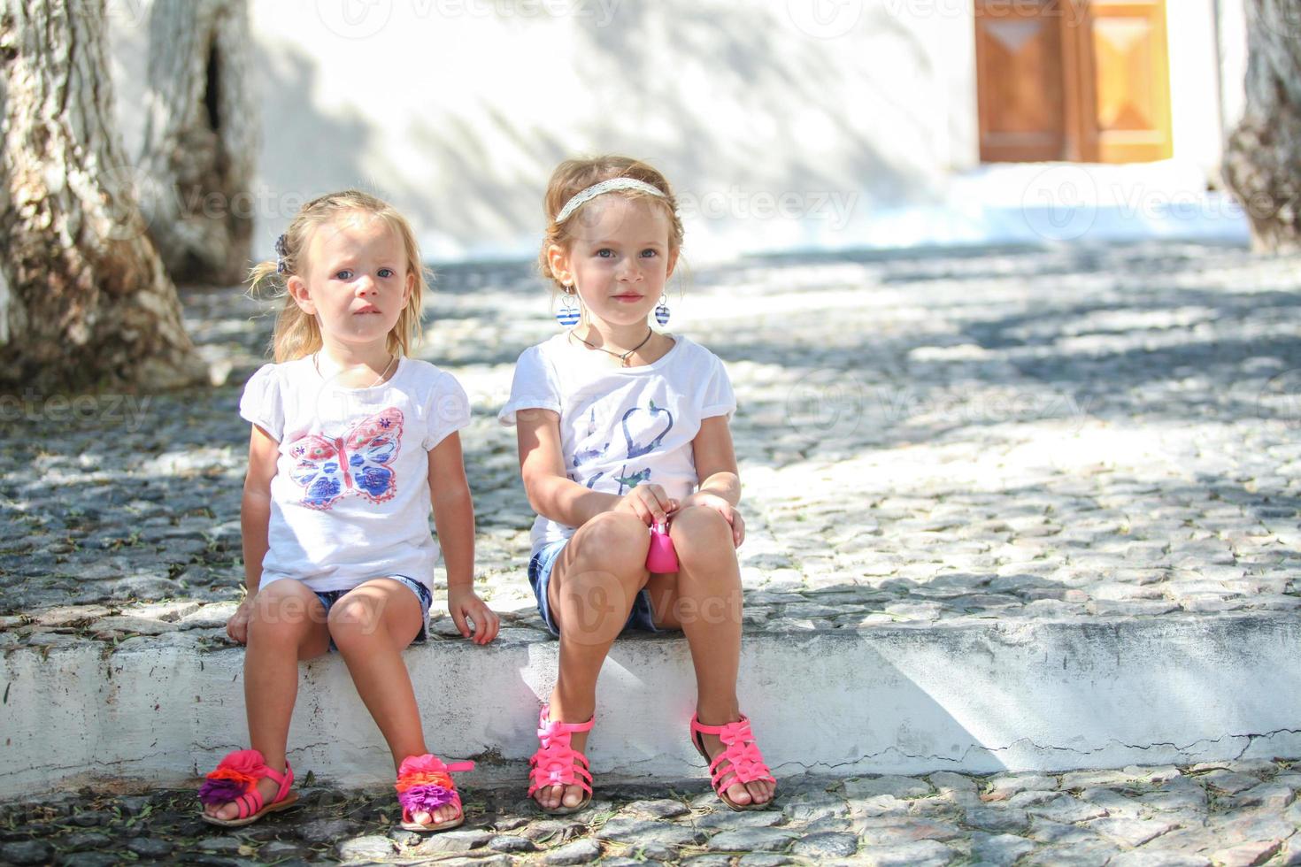 jóvenes encantadoras chicas sentadas en la calle en el antiguo pueblo griego de emporio, santorini foto