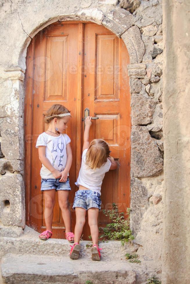 Little cute sisters near old door in Greek village of Emporio, Santorini photo