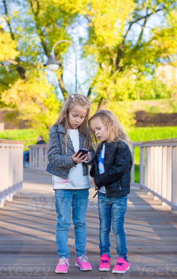 Adorable little girls at warm autumn day outdoors photo