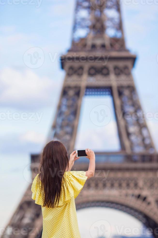 mujer joven haciendo foto por teléfono de fondo torre eiffel en parís