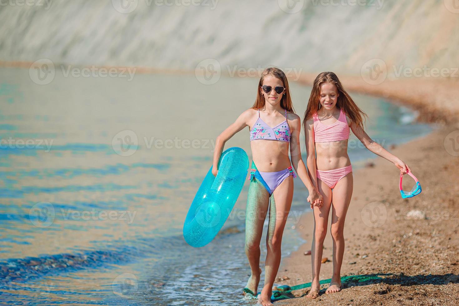 Little happy funny girls have a lot of fun at beach playing together photo