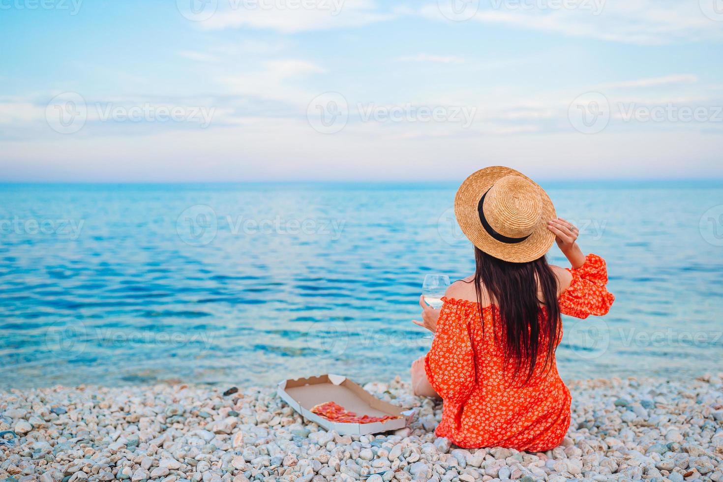 mujer haciendo un picnic con pizza en la playa foto