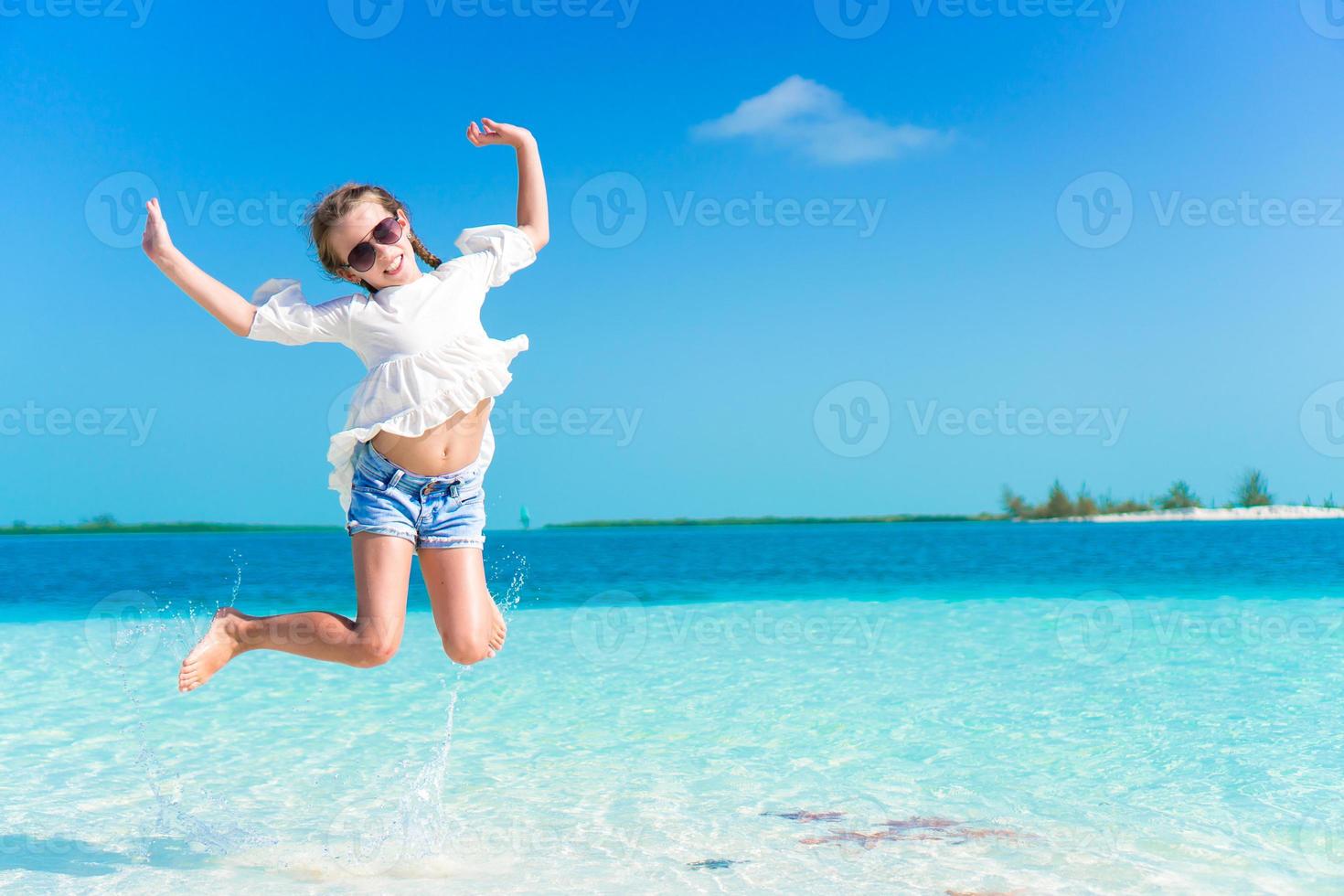 Adorable little girl having fun on the beach full of starfish on the sand photo