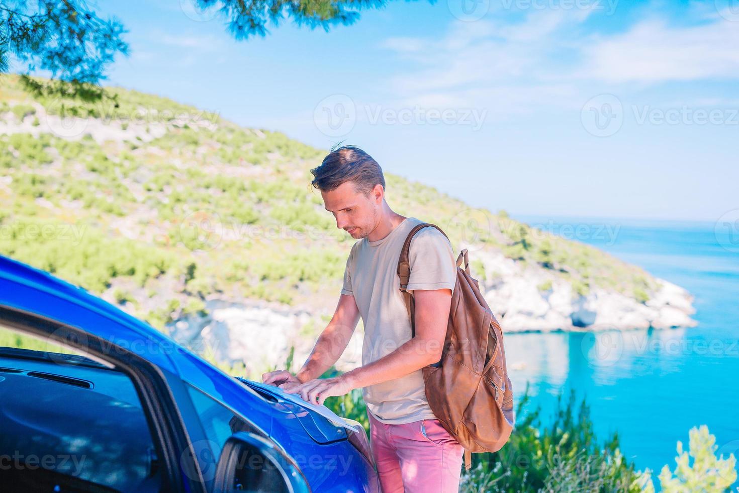 Young man with map travel by car on summer vacation photo