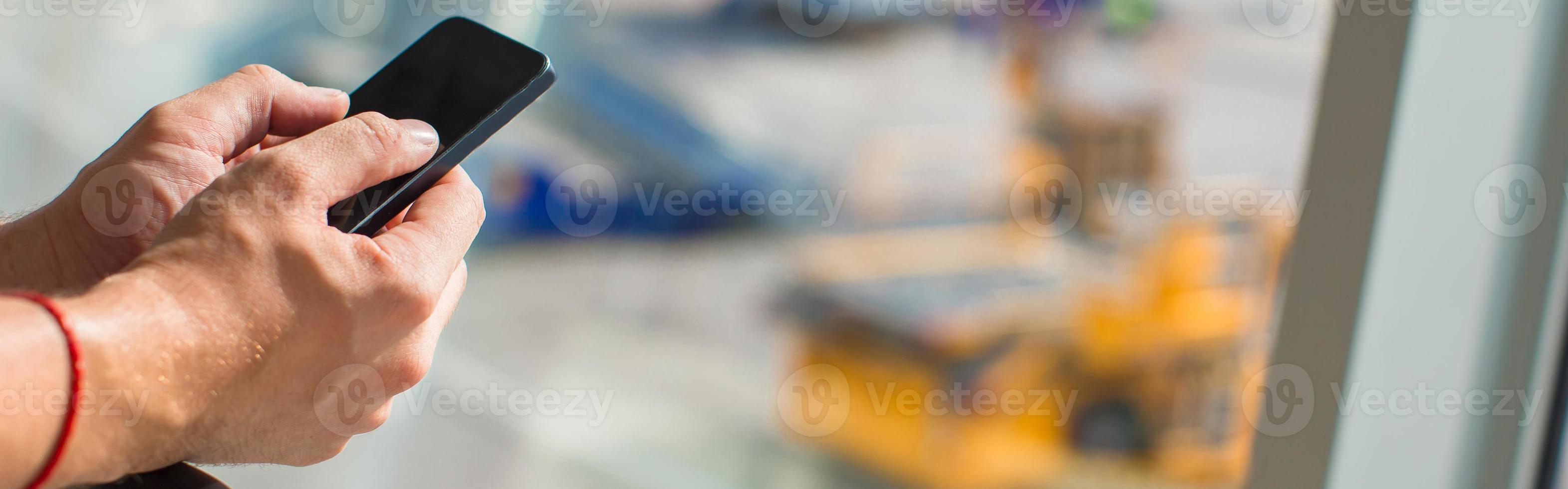 Close up man's hands using cellphone inside airport photo
