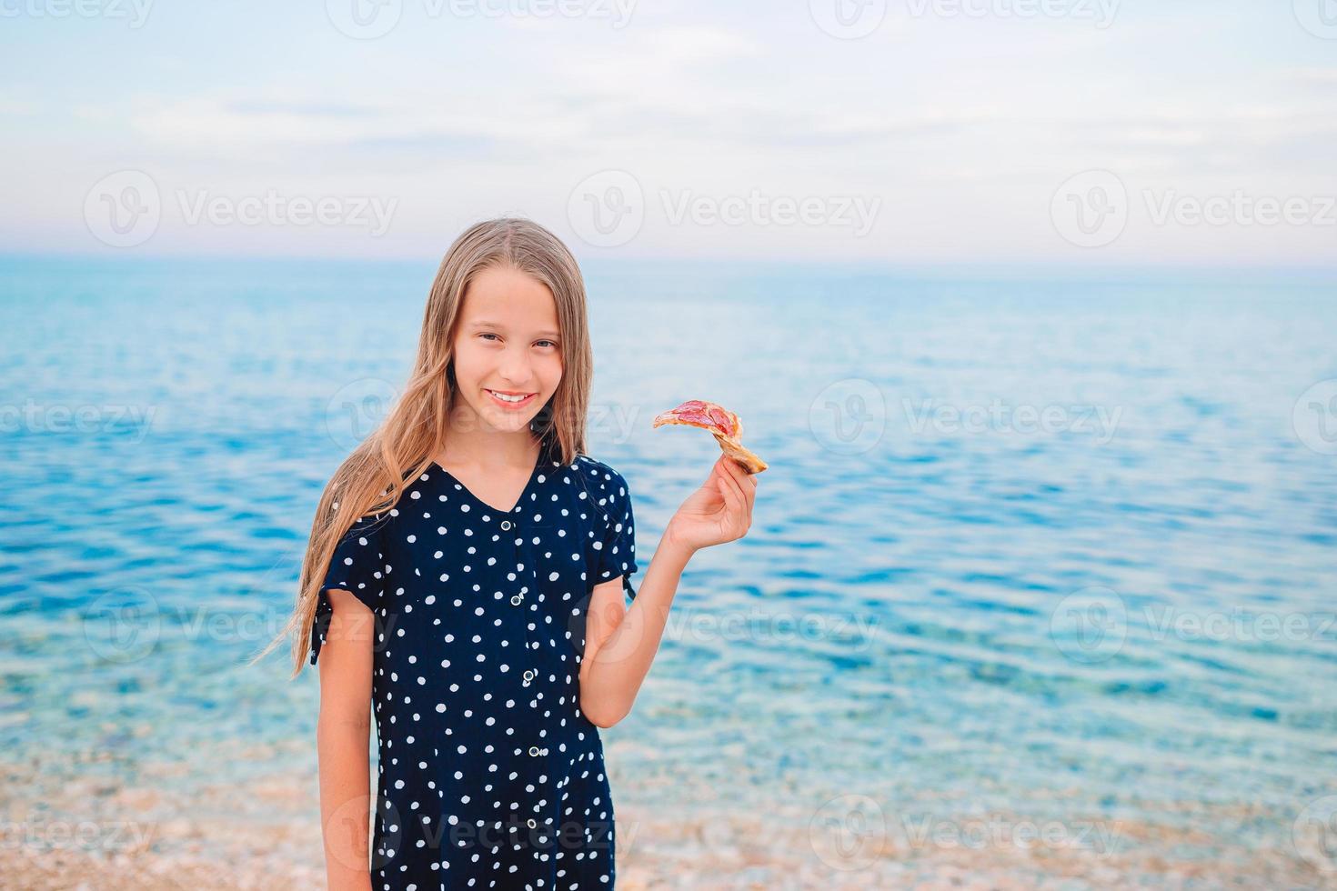 Happy girl having fun on the beach and eating pizza photo