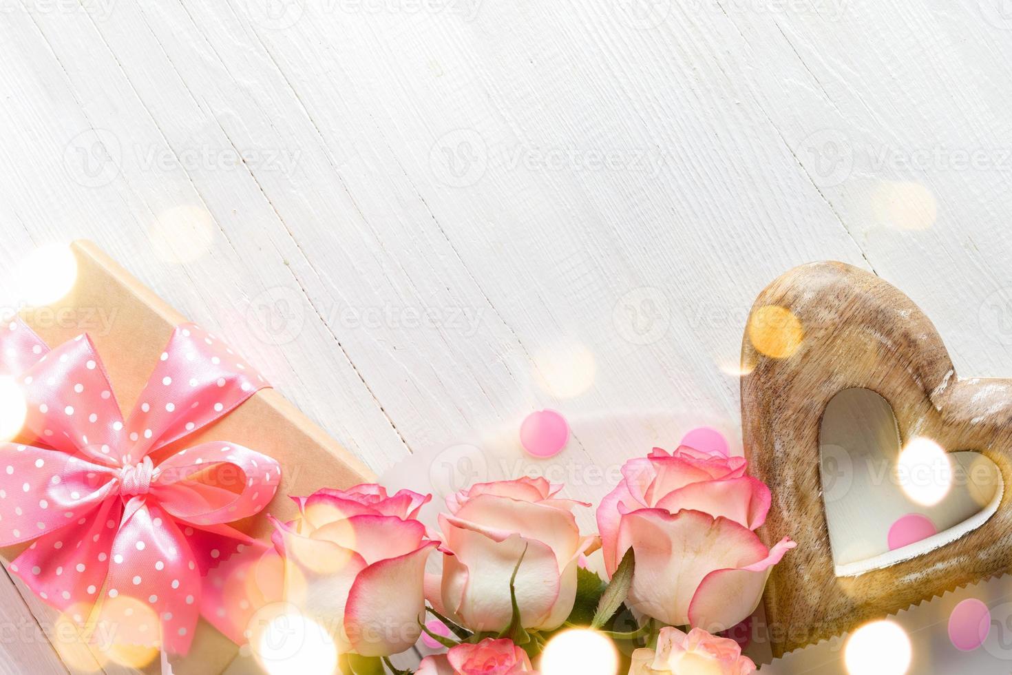 Gift box, pink roses, wooden heart on wood white backdrop with bokeh lights Festive card Copy space photo
