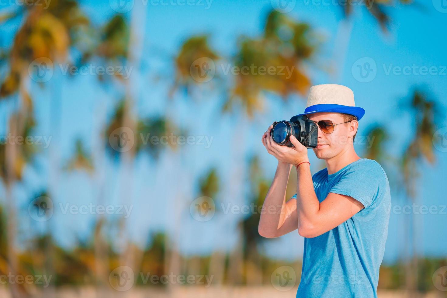 Young man photographed at camera on tropical beach photo