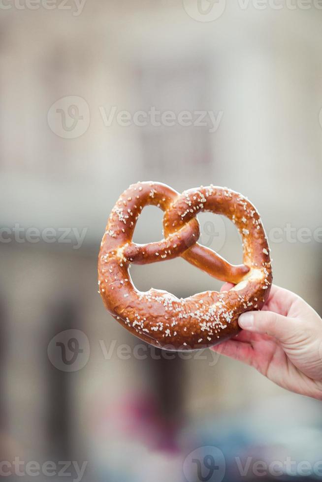 Salted pretzel in the hands of a man on background of the Vienna Opera photo