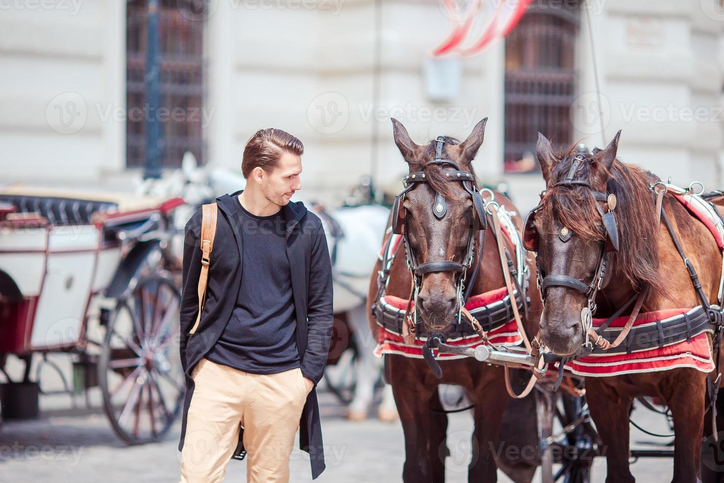 hombre turista disfrutando de un paseo por viena y mirando los dos caballos en el carruaje foto