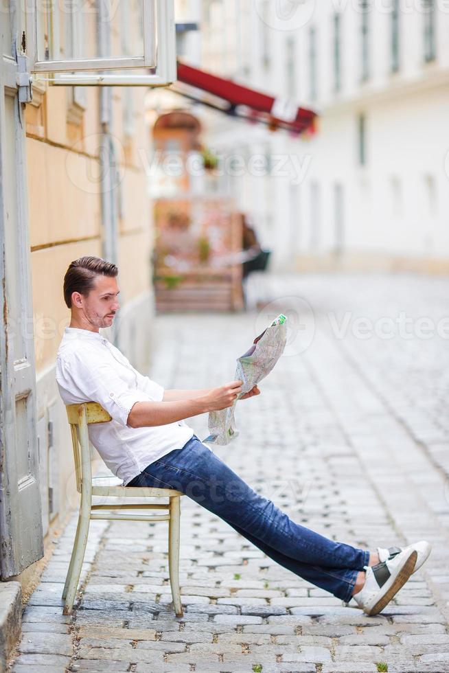 Man tourist with a city map and backpack in Europe street. Caucasian boy looking with map of European city. photo