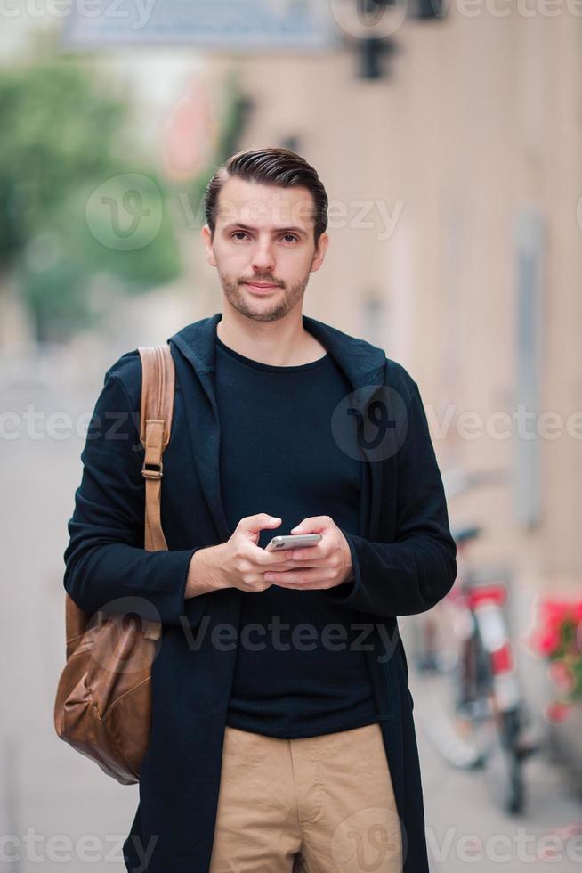 Man tourist with a city map and backpack in Europe street. Caucasian boy looking with map of European city. photo