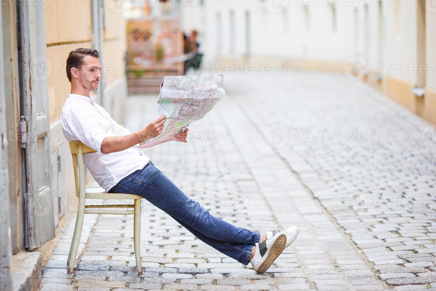 Man tourist with a city map and backpack in Europe street. Caucasian boy looking with map of European city. photo