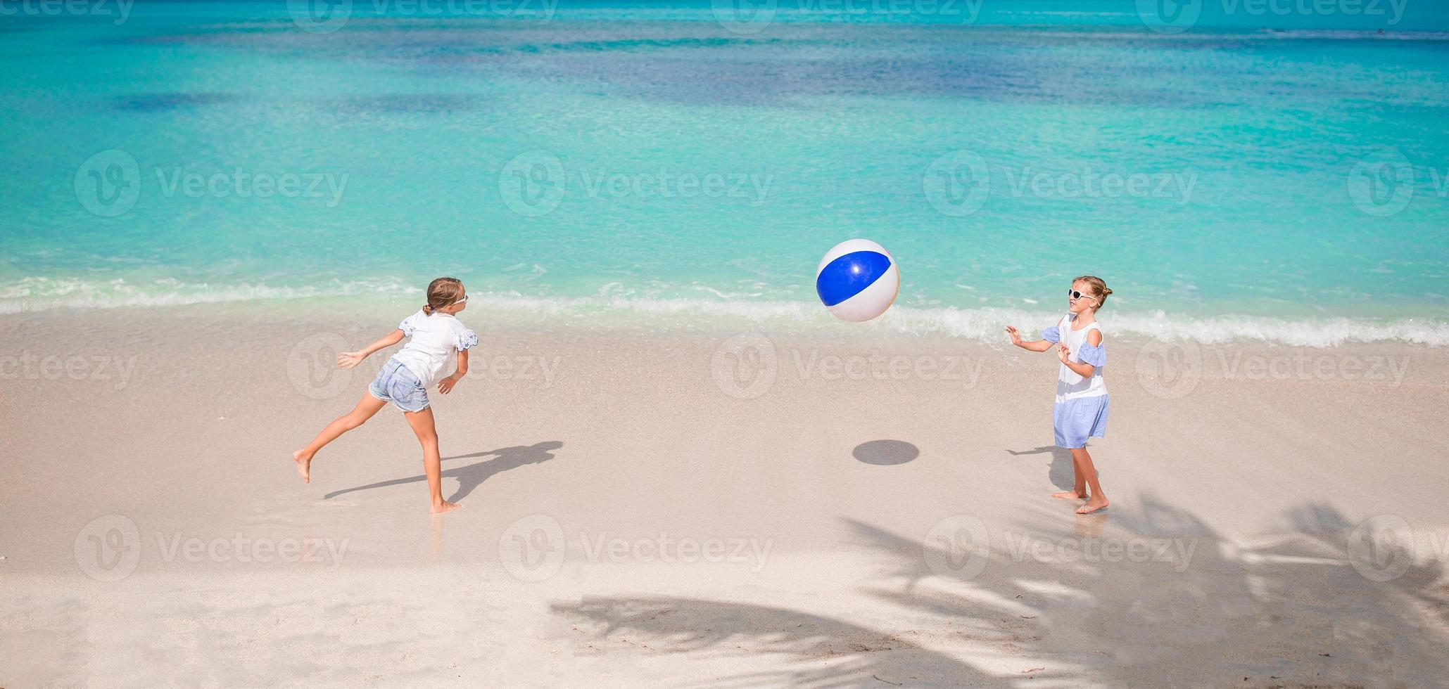 Little adorable girls playing with ball on the beach photo