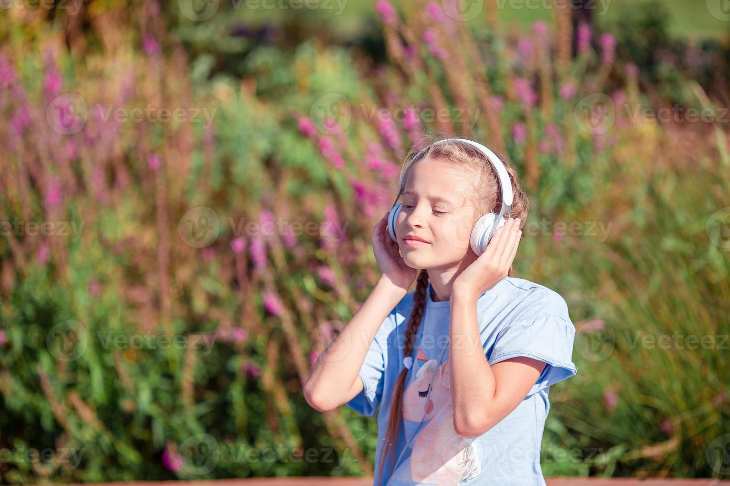 Little adorable girl listening music in the park photo