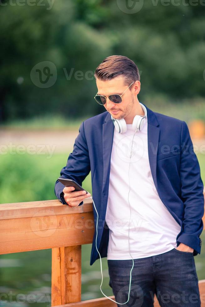 Man is reading text message on mobile phone while walking in the park photo