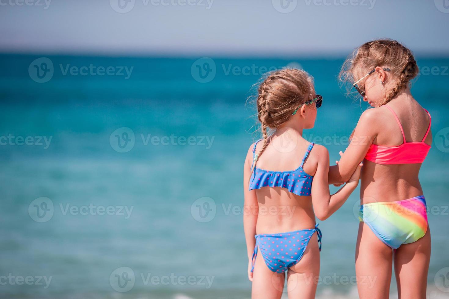 Two little happy girls have a lot of fun at tropical beach playing together photo