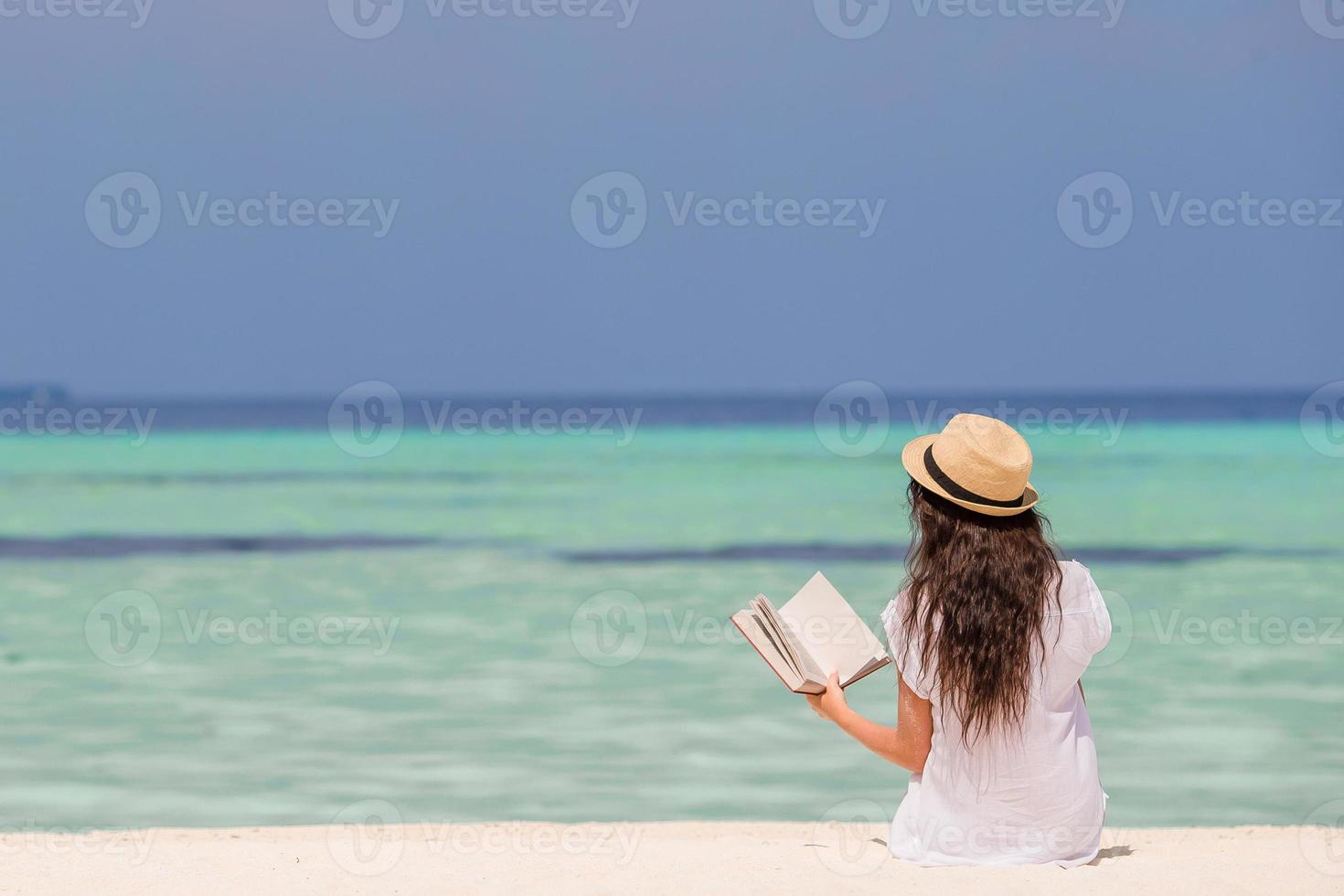 Portrait of a young woman relaxing on the beach, reading a book photo