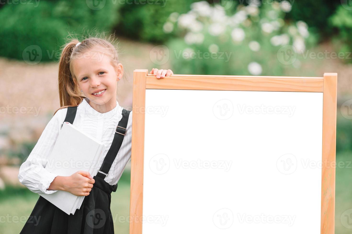 Happy little schoolgirl with a chalkboard outdoor photo