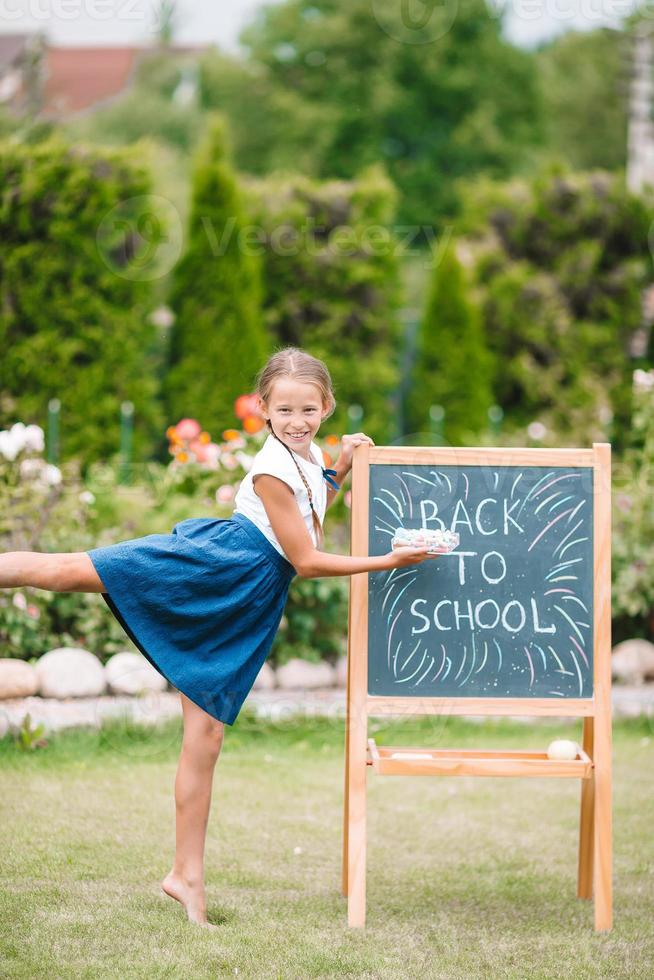 Happy little schoolgirl with a chalkboard outdoor photo