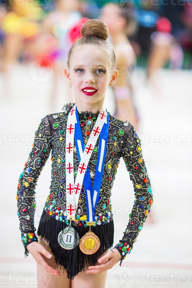 hermosa pequeña gimnasta entrenando en la alfombra y lista para las competiciones foto