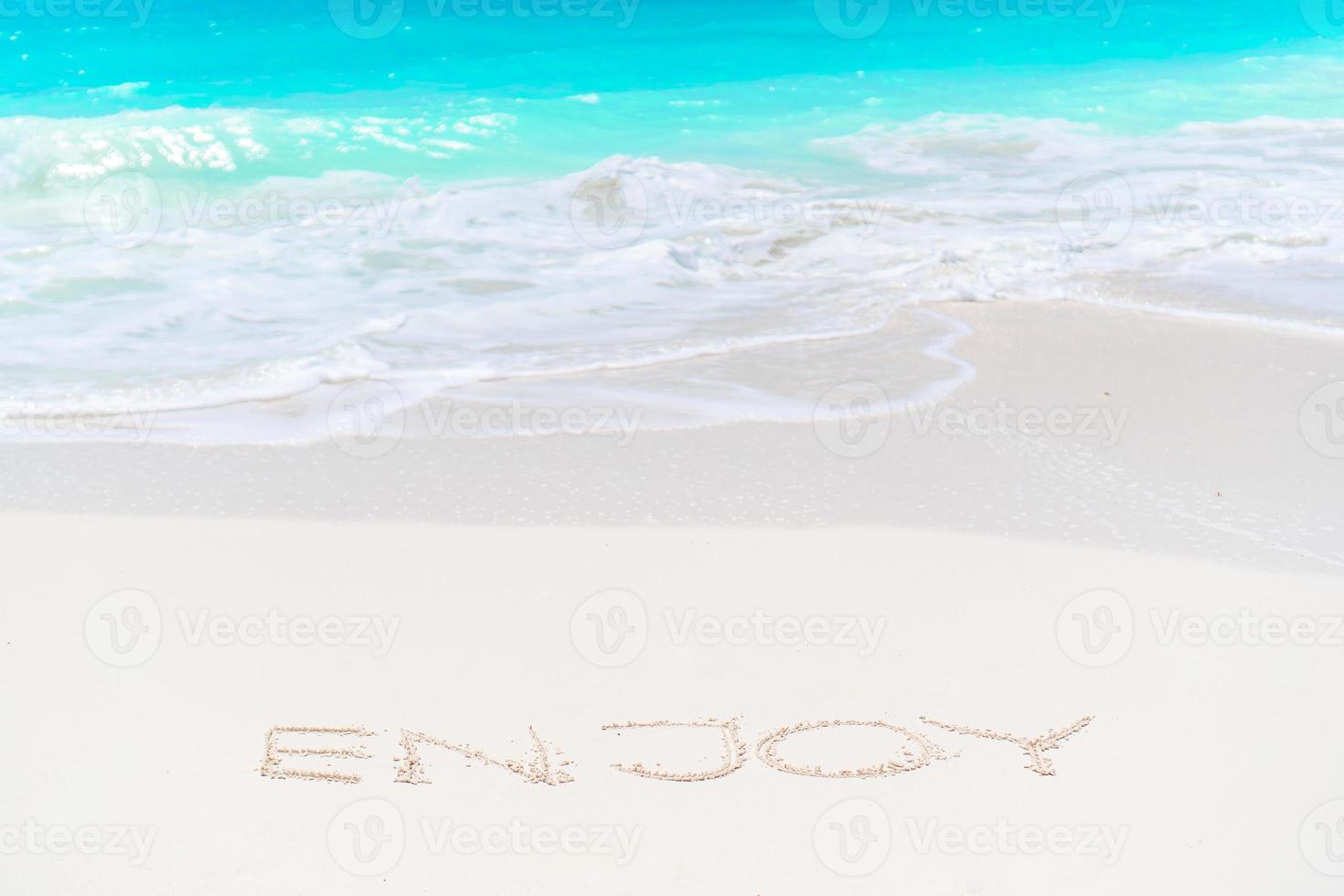 Dream written on sandy beach with soft ocean wave on background photo